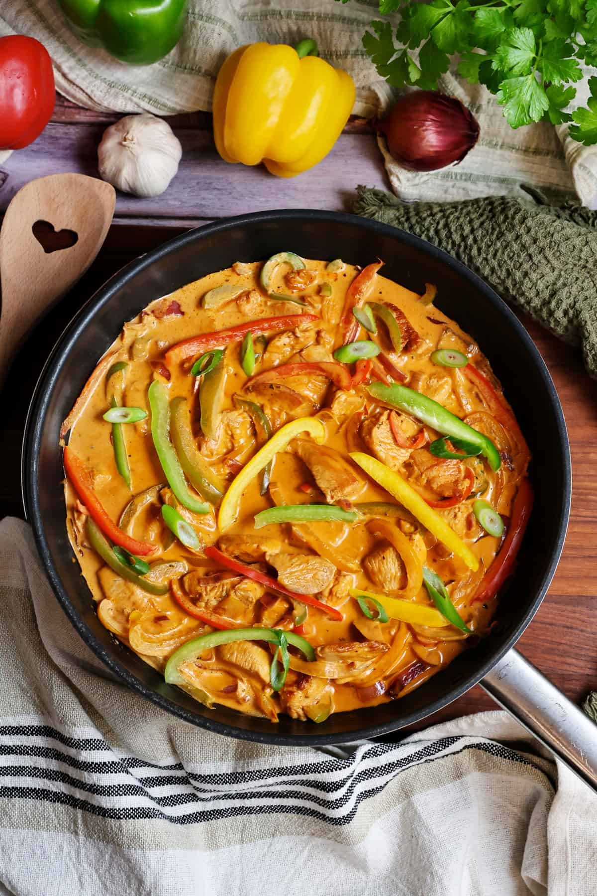 Eine Hähnchen-Paprika-Pfanne. Darüber Gemüse als Deko.